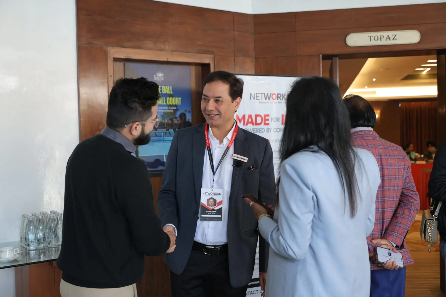 Two members shaking hands at a Networkers meeting in the Topaz hall, Hotel Sayaji, Indore